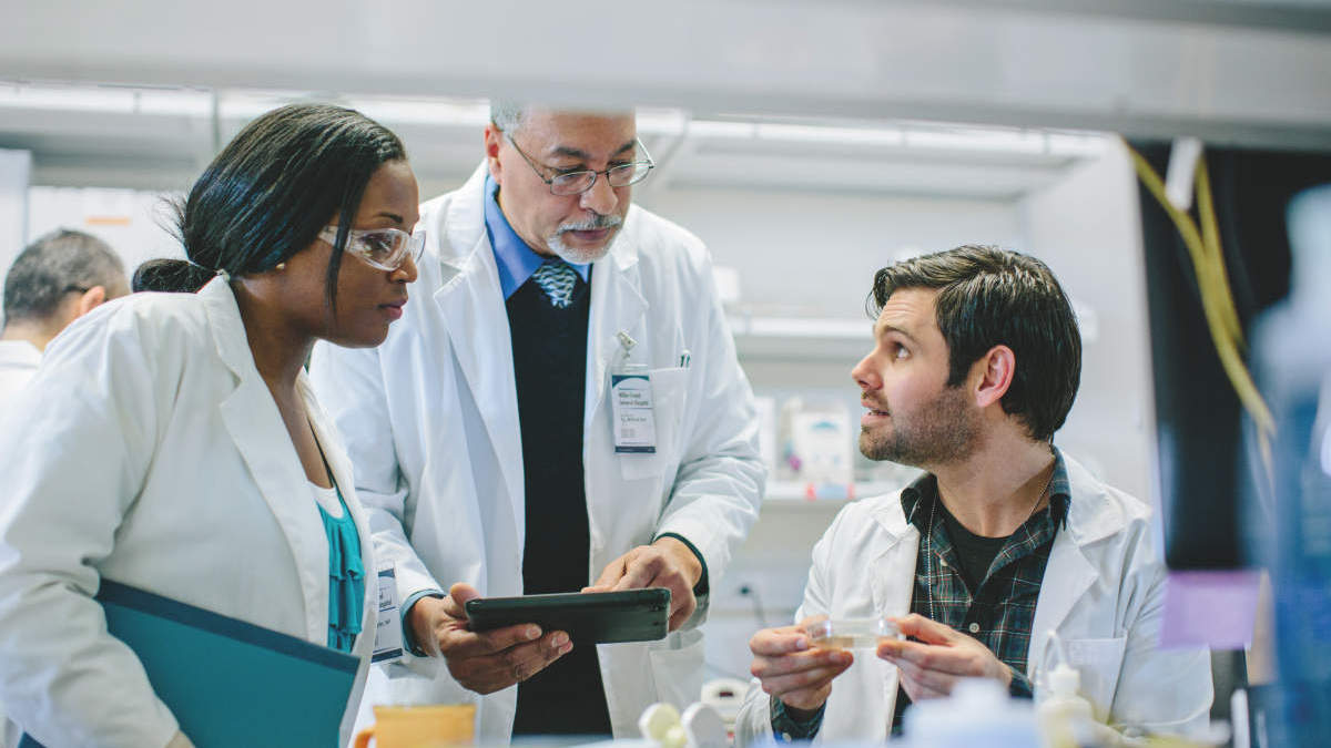 Male doctor discussing with coworkers in hospital, Cancer Research